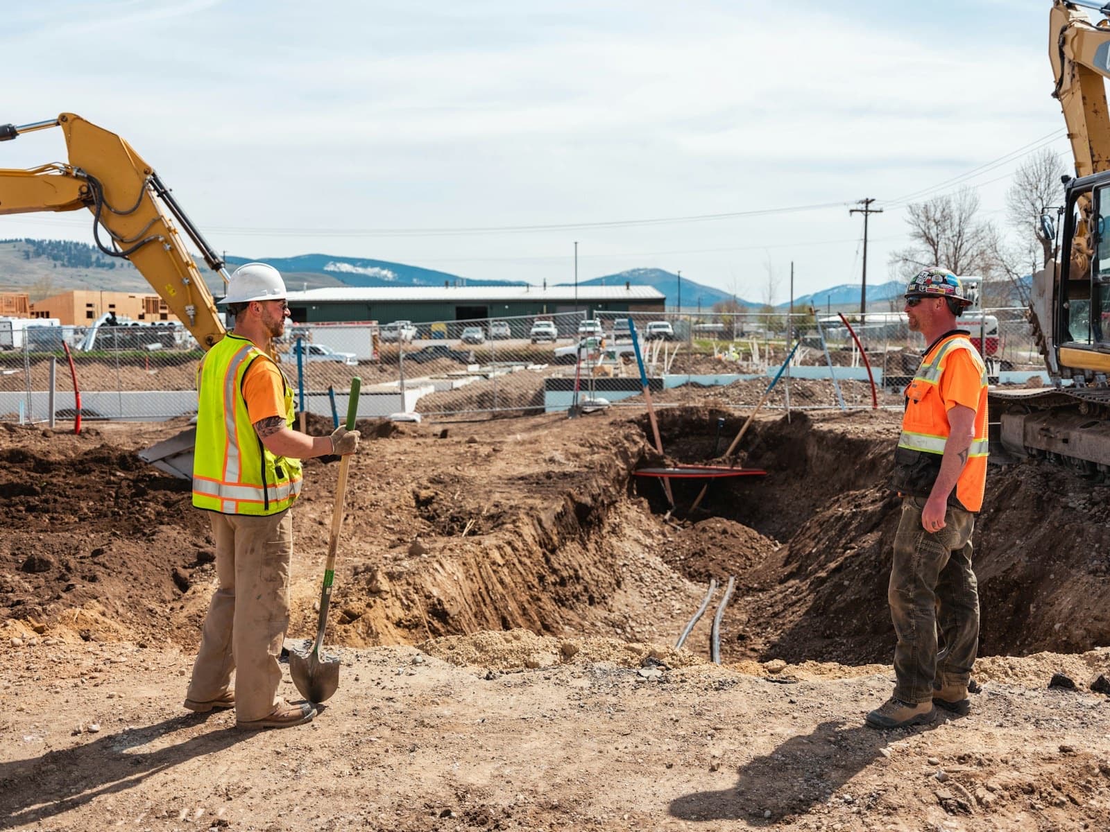 Construction workers in hi-vis with excavators on a building site